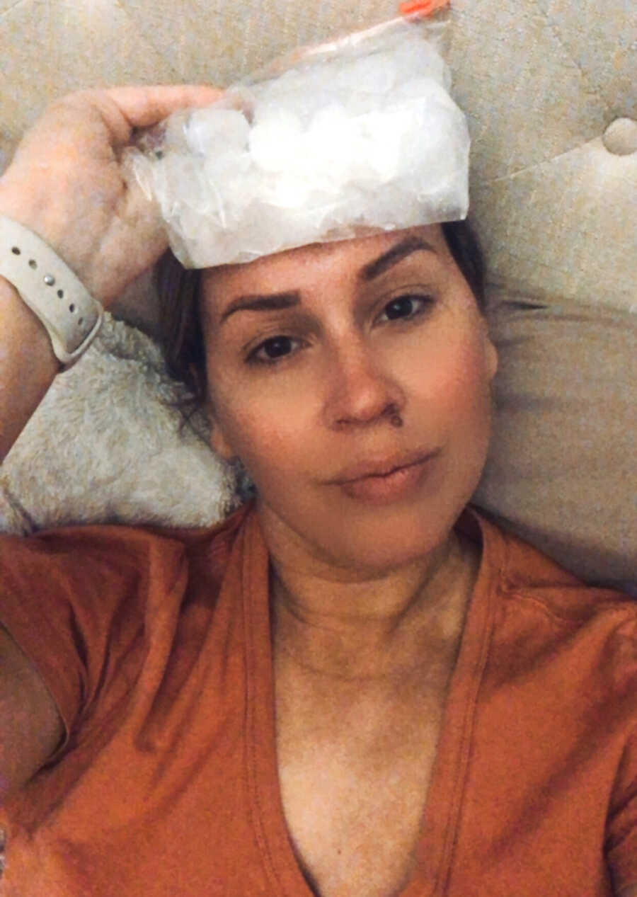 woman with chronic headaches holds bag of ice to her forehead