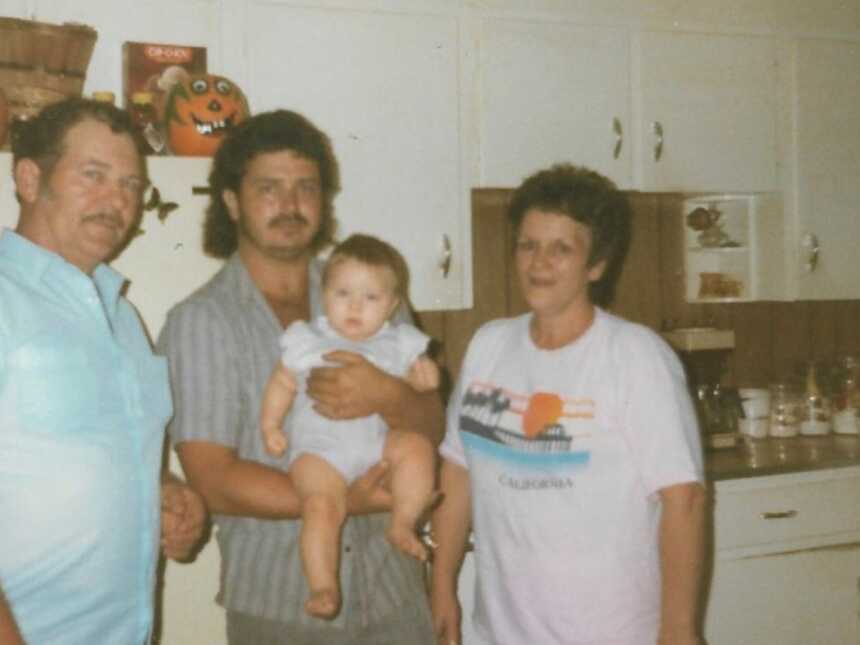 Kinship family members standing in kitchen with one holding baby