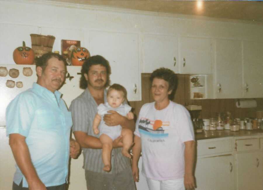 Kinship family members standing in kitchen with one holding baby