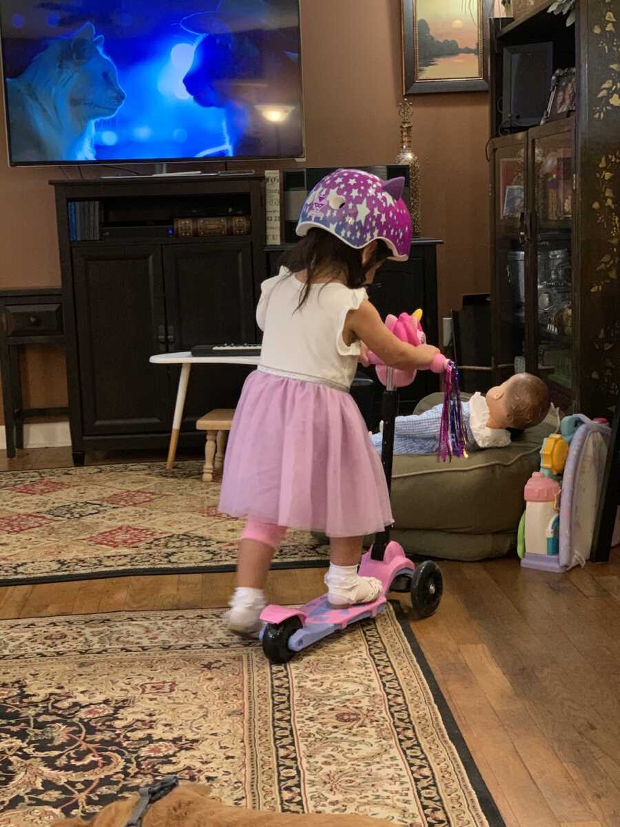 foster child playing on a scooter wearing a helmet