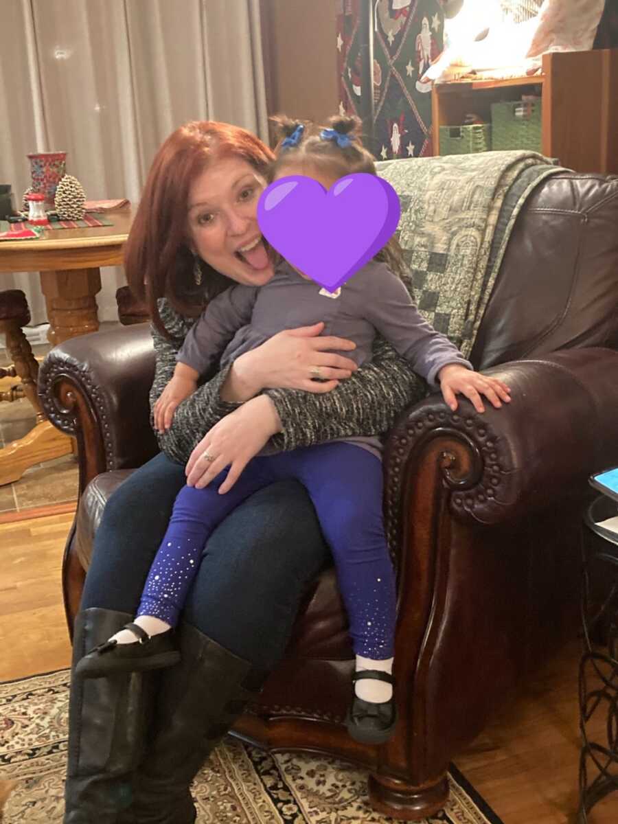 foster mom sits on chair with foster child on lap