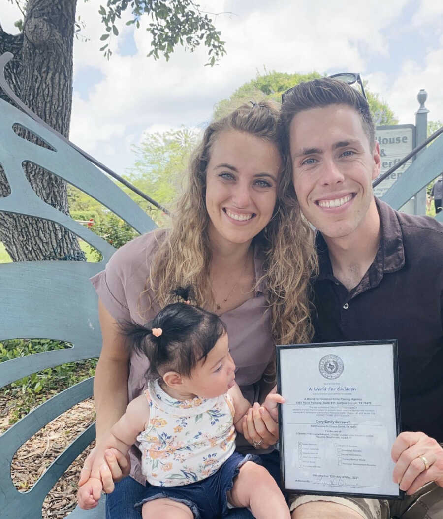 Adoptive parents sitting with their adoptive daughter while holding a foster license 