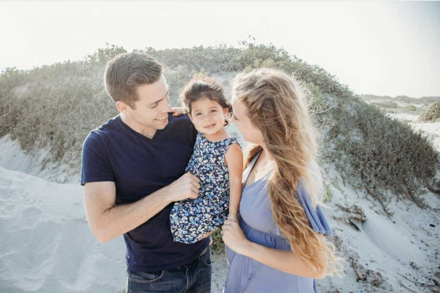 Foster parents holding adoptive daughter at the beach