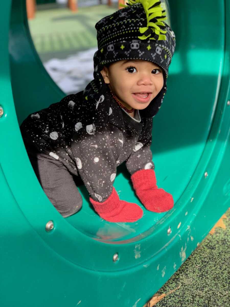 foster son inside playground tube with red gloves