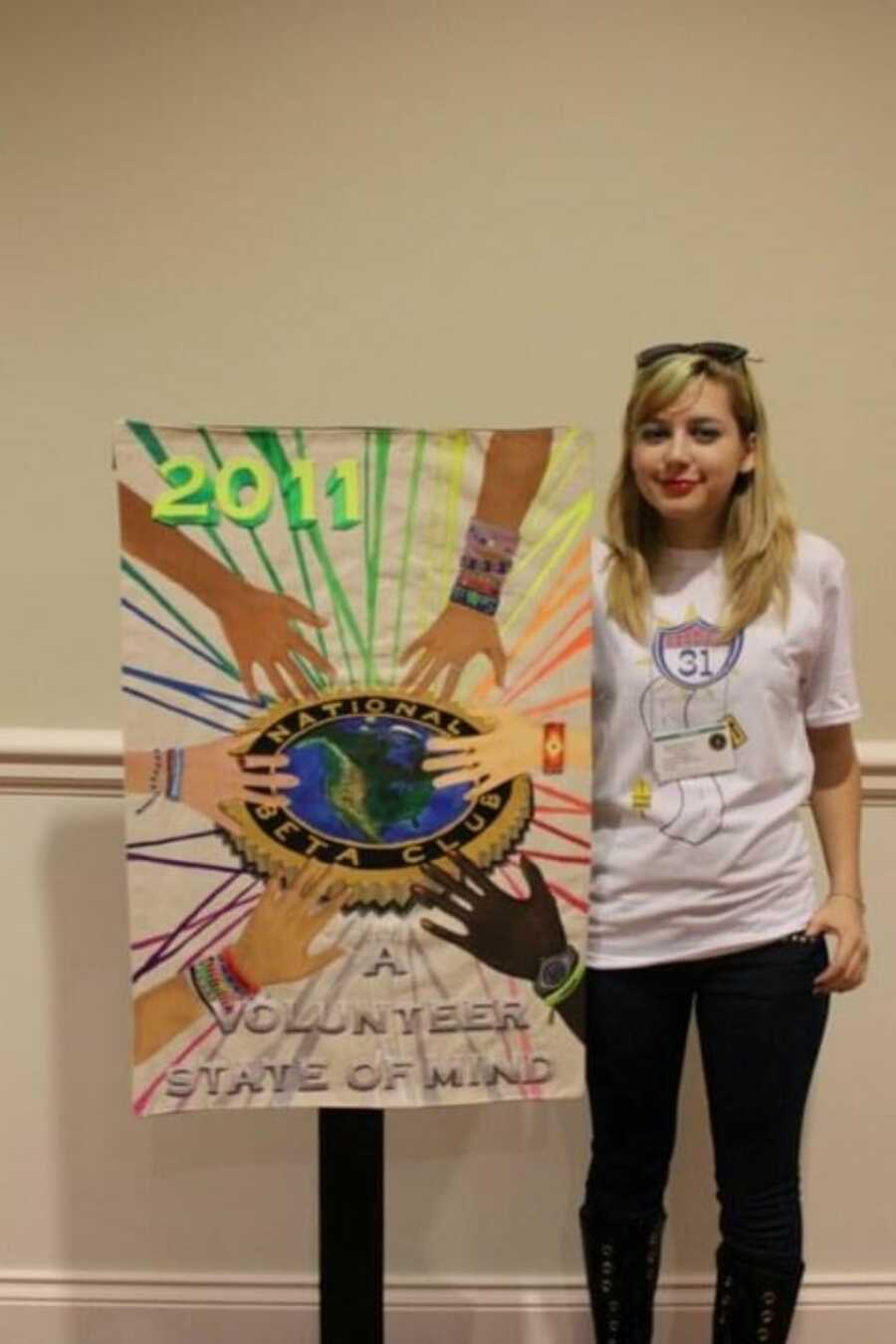 domestic abuse survivor in highschool next to colorful volunteer poster