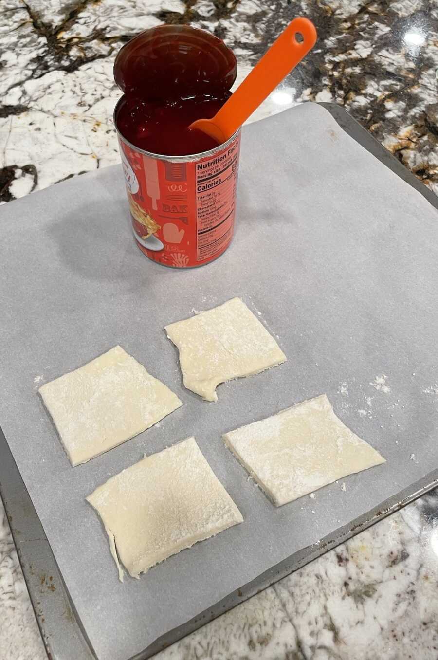 kolaches dough squares on baking sheet next to cherry filling