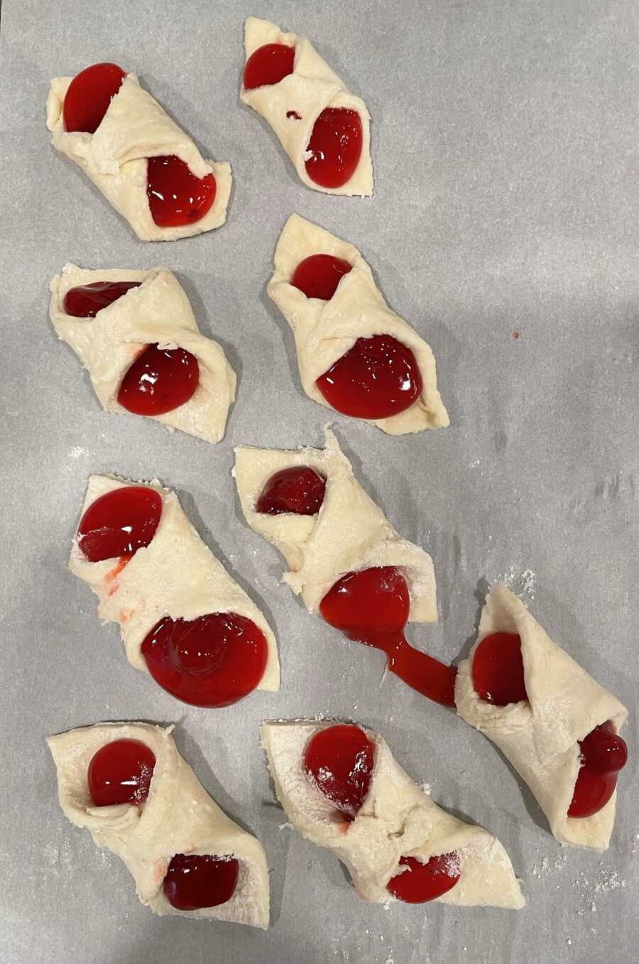 kolaches folded with filling on parchment baking sheet