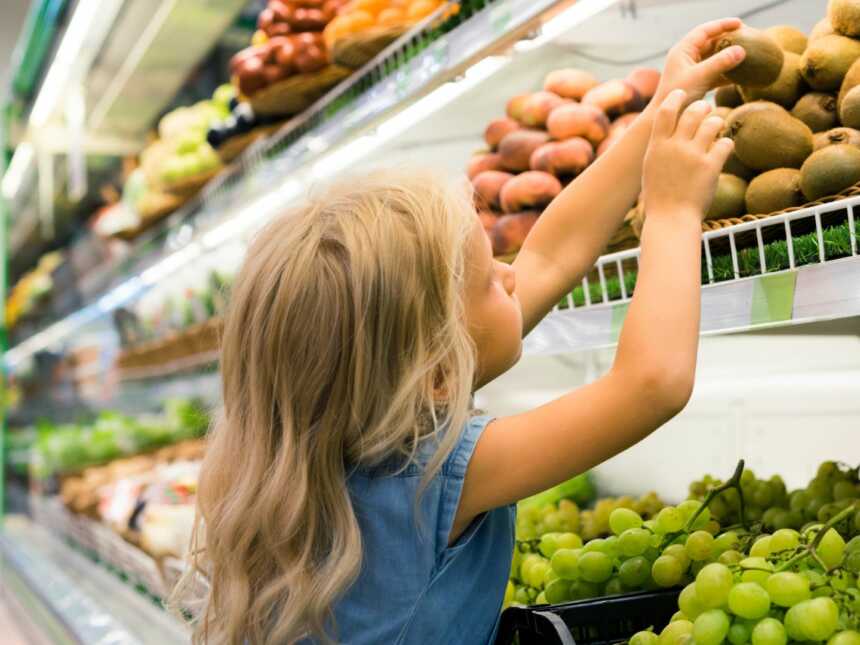young girl in grocery store choosing produce