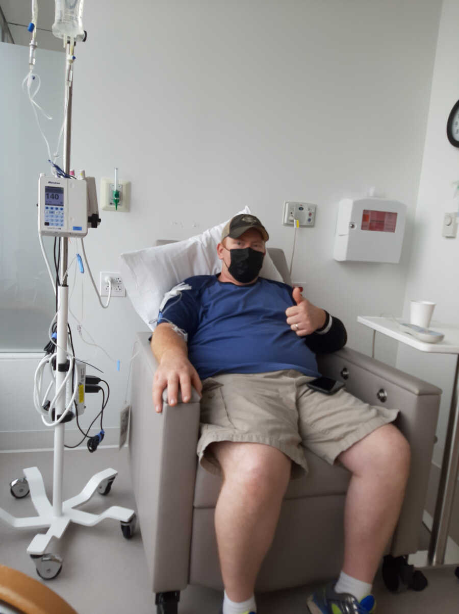 man with melanoma sits in chair with IV next to him