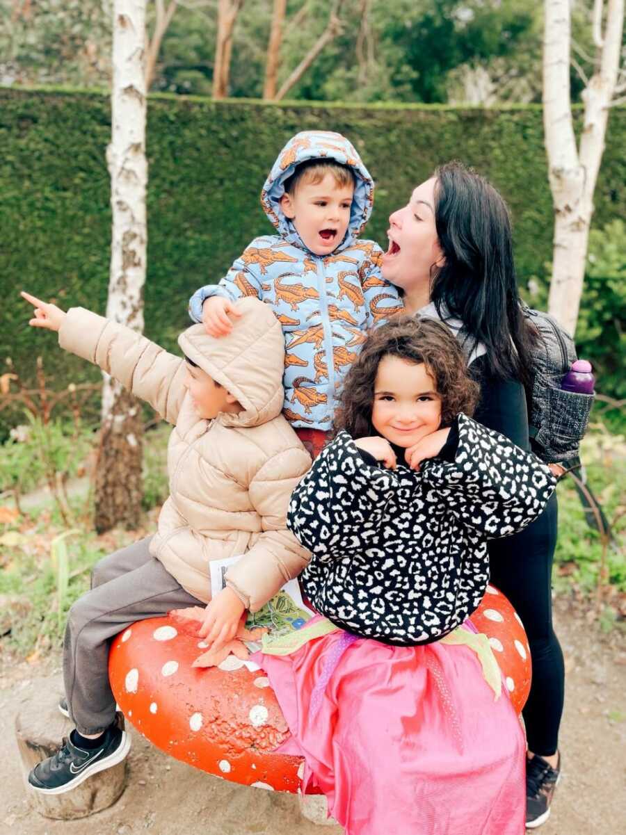 A mom with her three kids outside making silly faces 