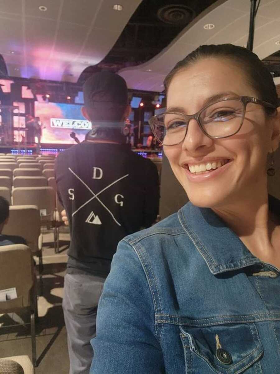 Mother smiling at concert with stage in background 