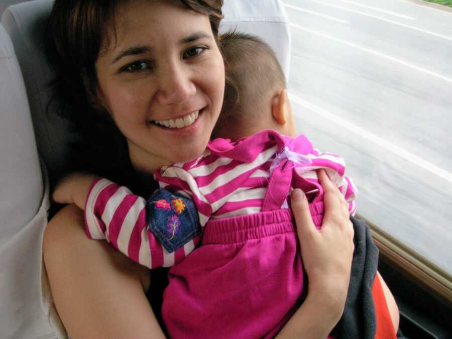 mother holding adopted baby against her chest on a train