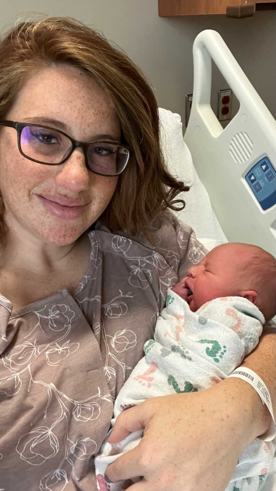 Mother smiling while holding newborn baby after child birth 