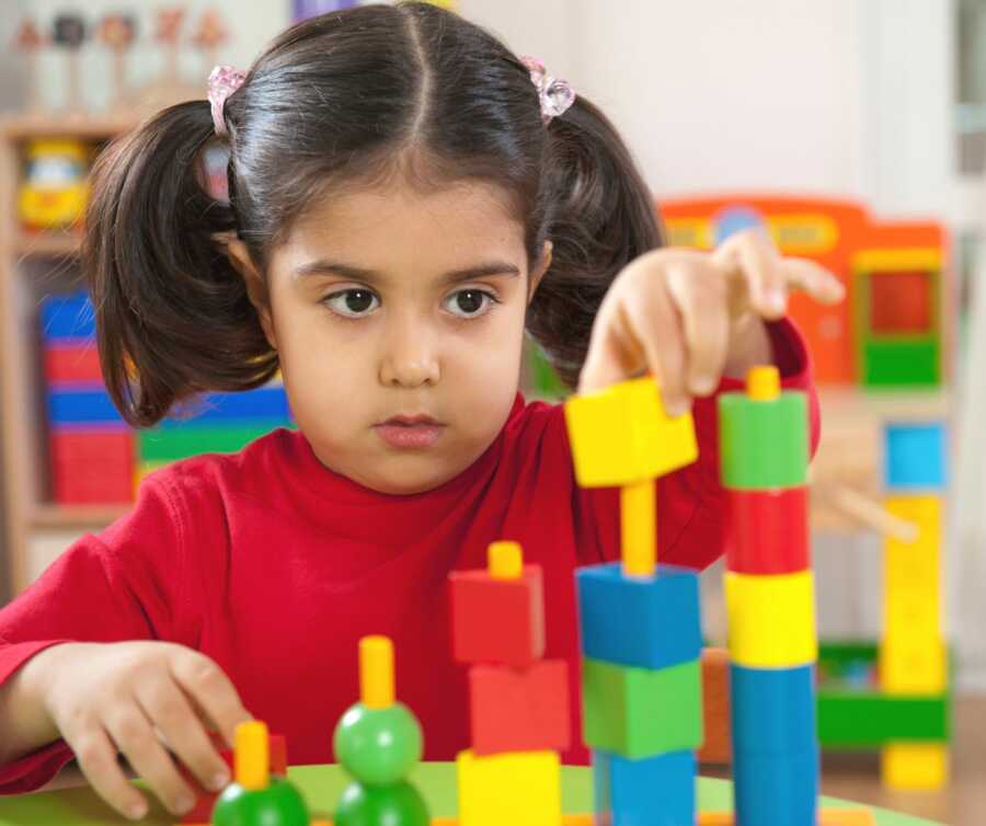 preschool girl plays with building blocks