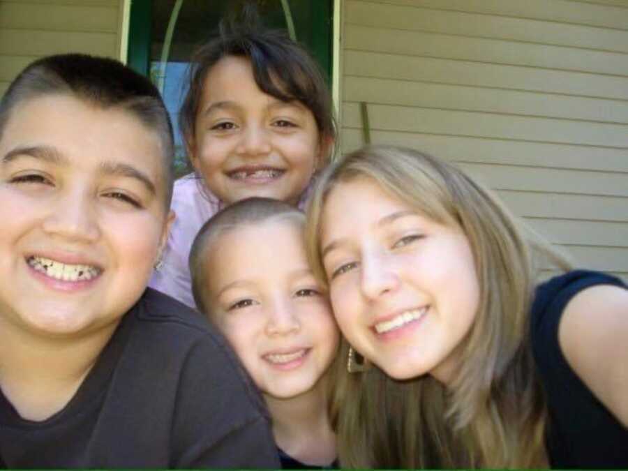 domestic abuse survivor with 3 siblings smiling at camera 