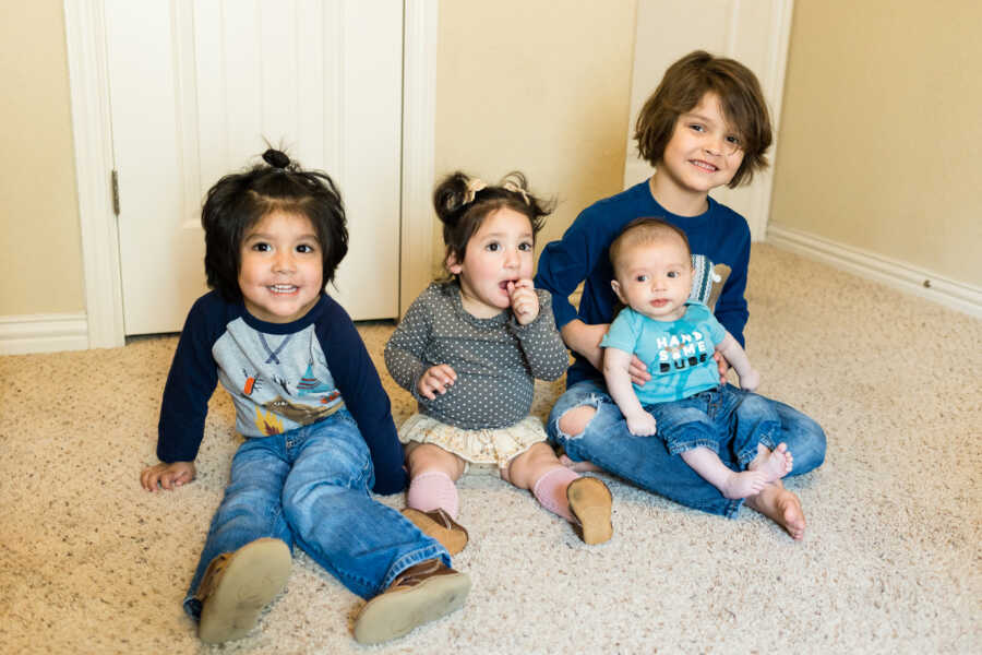 foster siblings sitting on floor grouped together