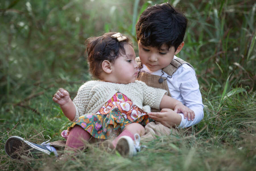 siblings in foster care sitting together in the grass