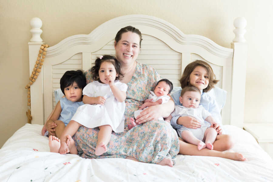 single foster mom sits on bed with 5 placements