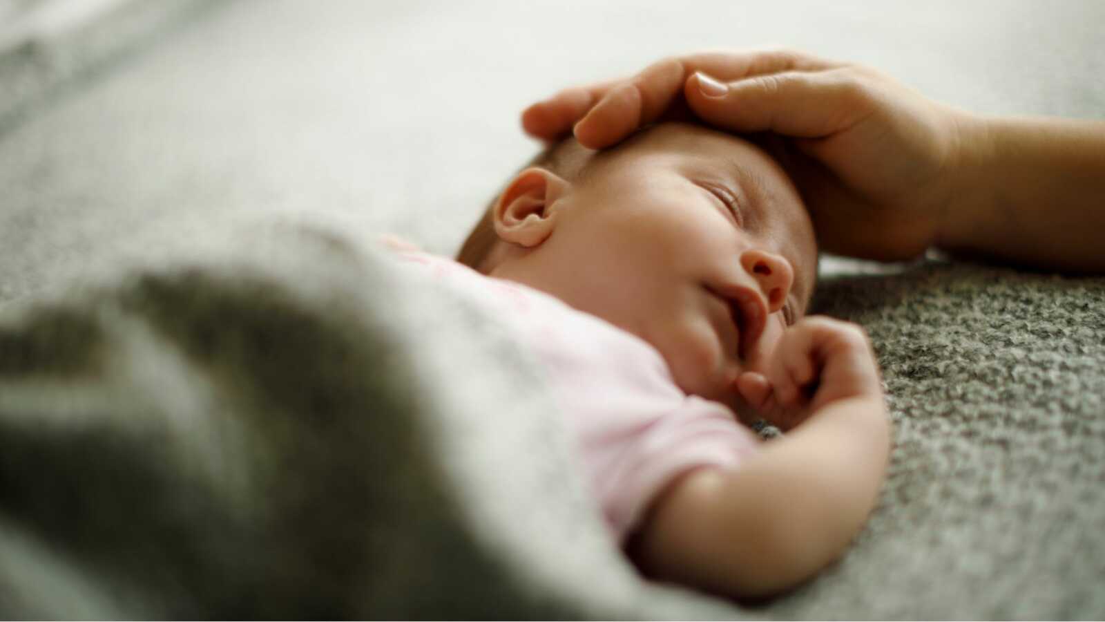 sleeping newborn with adoptive mother's hand on their head