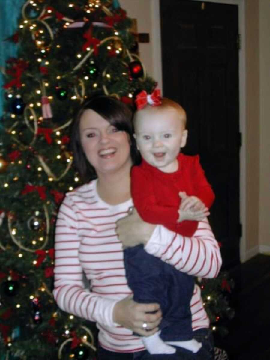 sober mom holding baby beside Christmas tree