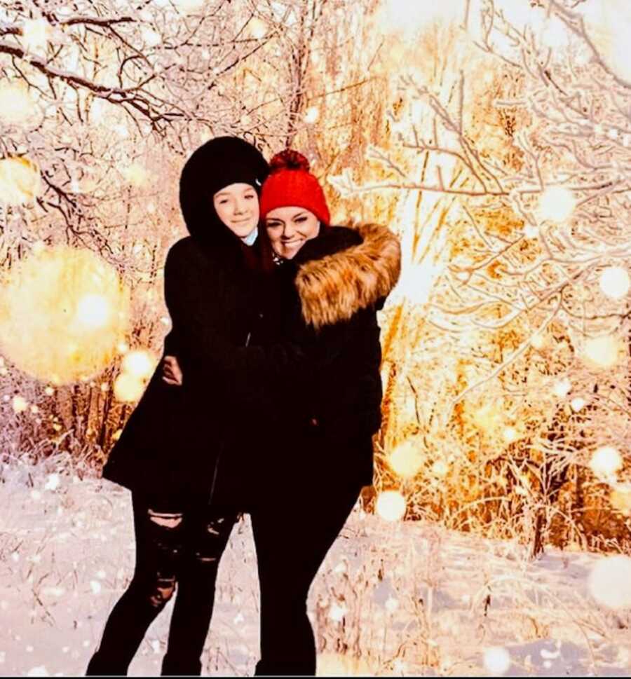 sober mom and daughter hugging outside in front of snowy trees