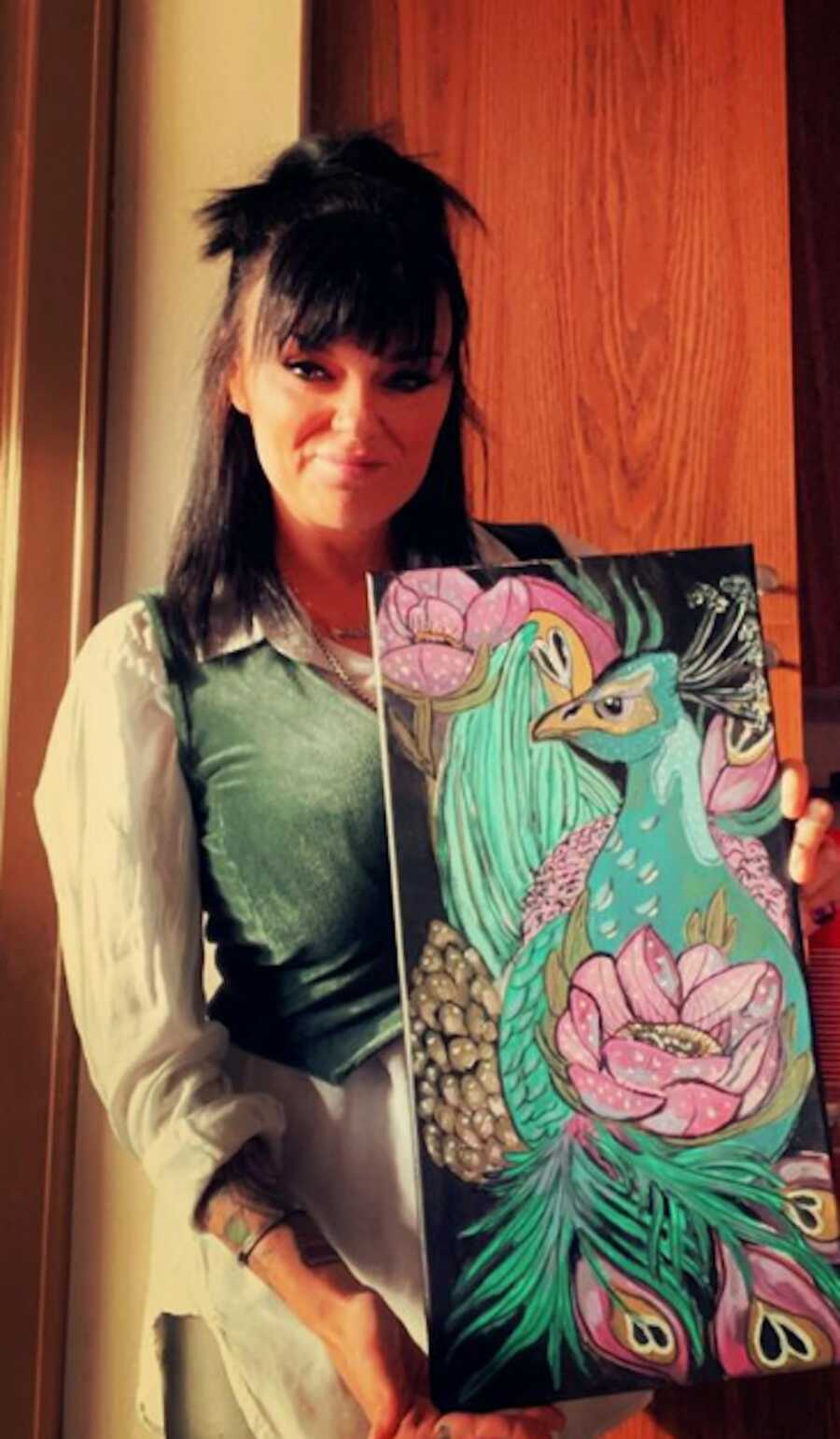 sober mom holding a colorful painting of a bird