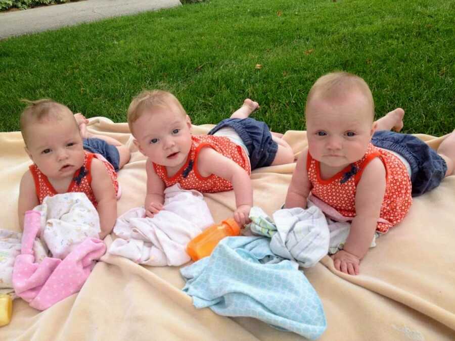 triplet children of sober mom in matching outfits on yellow blanket