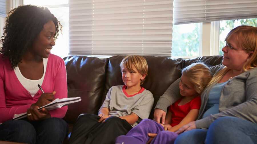 social worker sits on couch with adoptive family