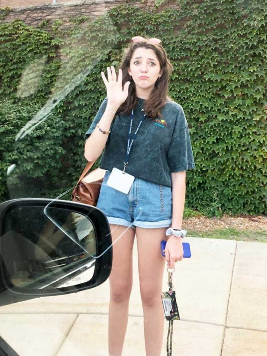 Teenage daughter waving goodbye to mother as she leaves for school.