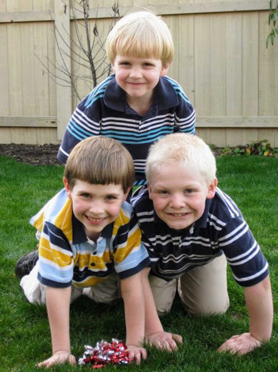 three young boys on top on each other in pyramid shape