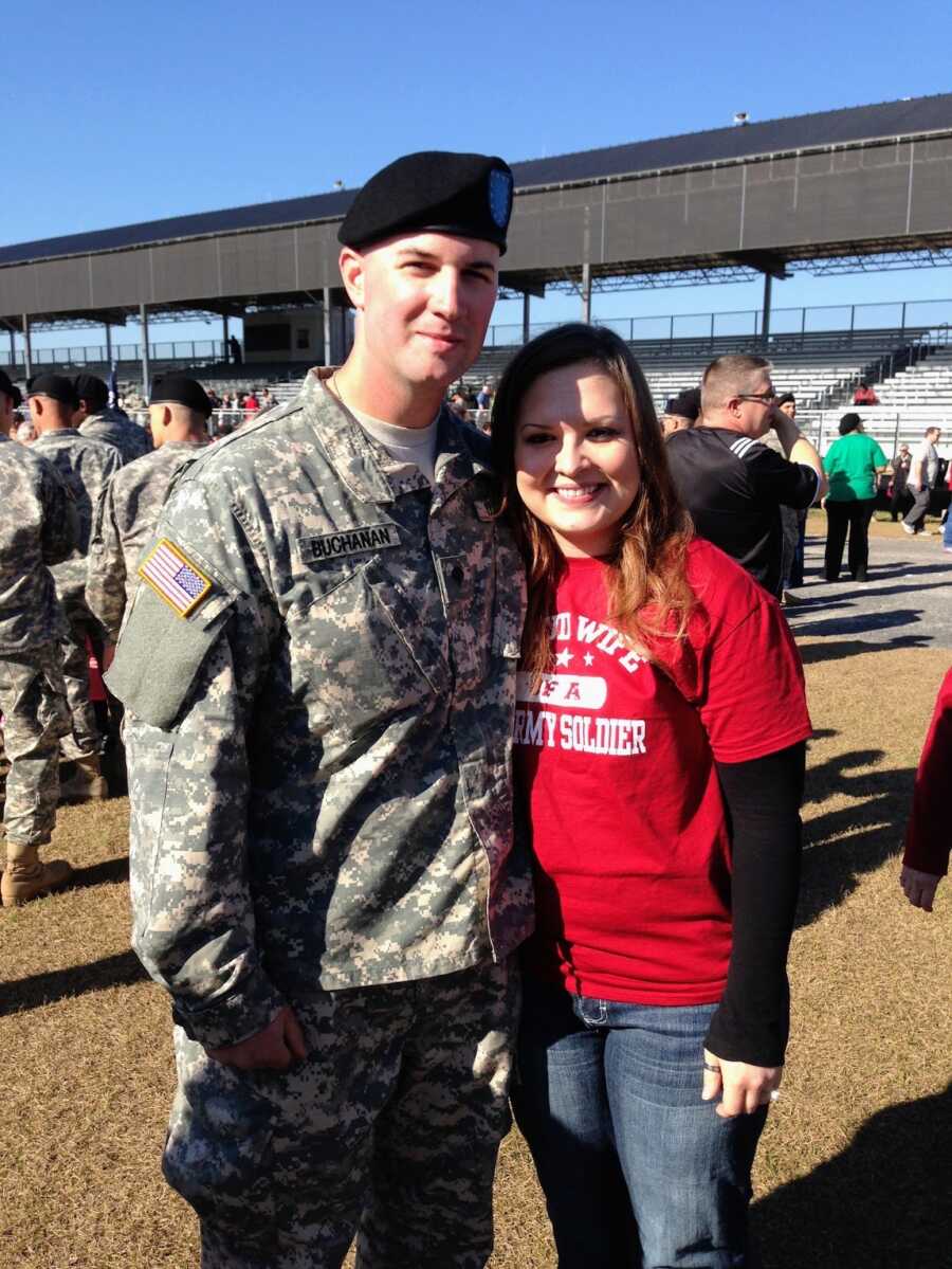wife and her military husband in a sports field with other soldiers
