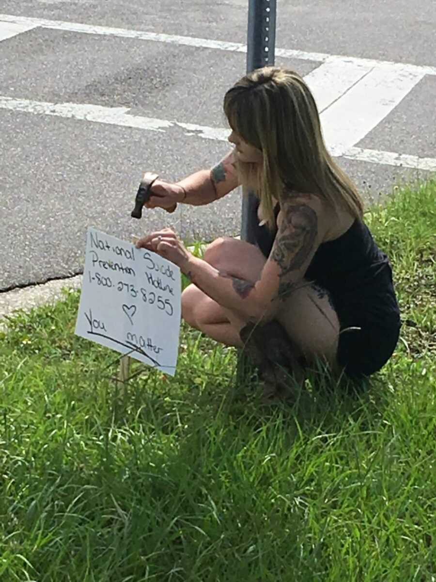 suicide attempt survivor hammering down menatl health sign into grass