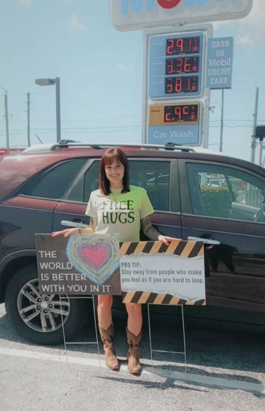 suicide attempt survivor wearing green shirt standing with two mental health signs