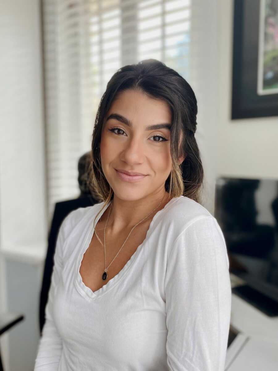 Sober young woman wearing white long sleeve looking into camera