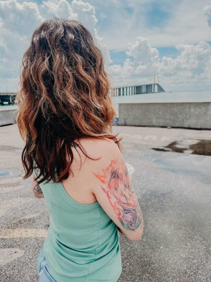 domestic violence survivor wearing blue shirt facing away from camera 