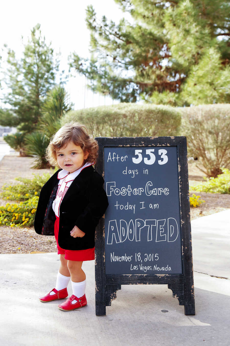 young boy on his adoption day next to a sign