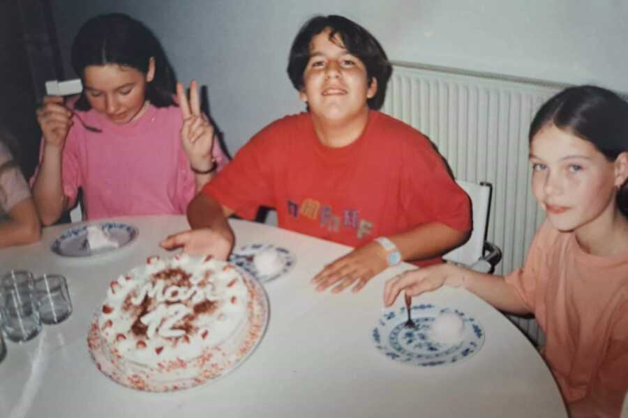 sexual abuse and eating disorder survivor wearing red shirt sitting in front of birthday cake