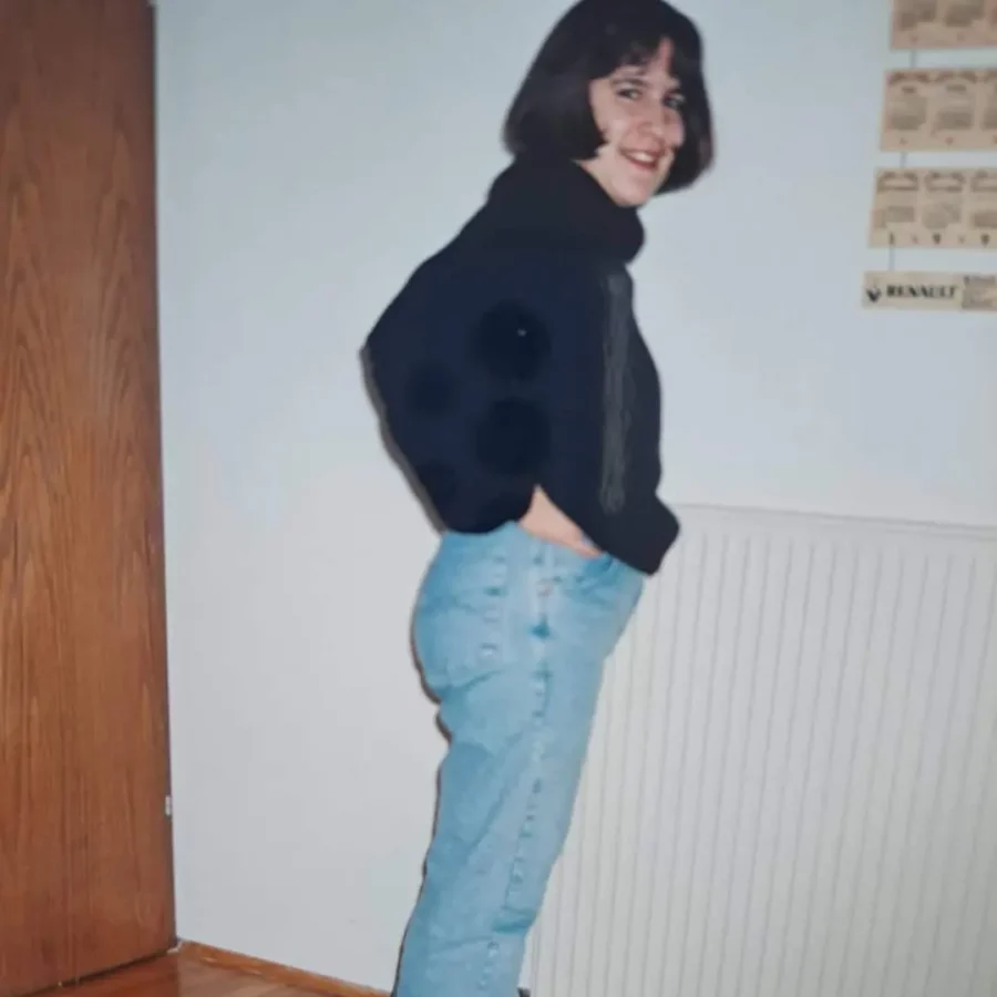 sexual abuse and eating disorder survivor wearing blue jeans and navy sweater smiling at camera