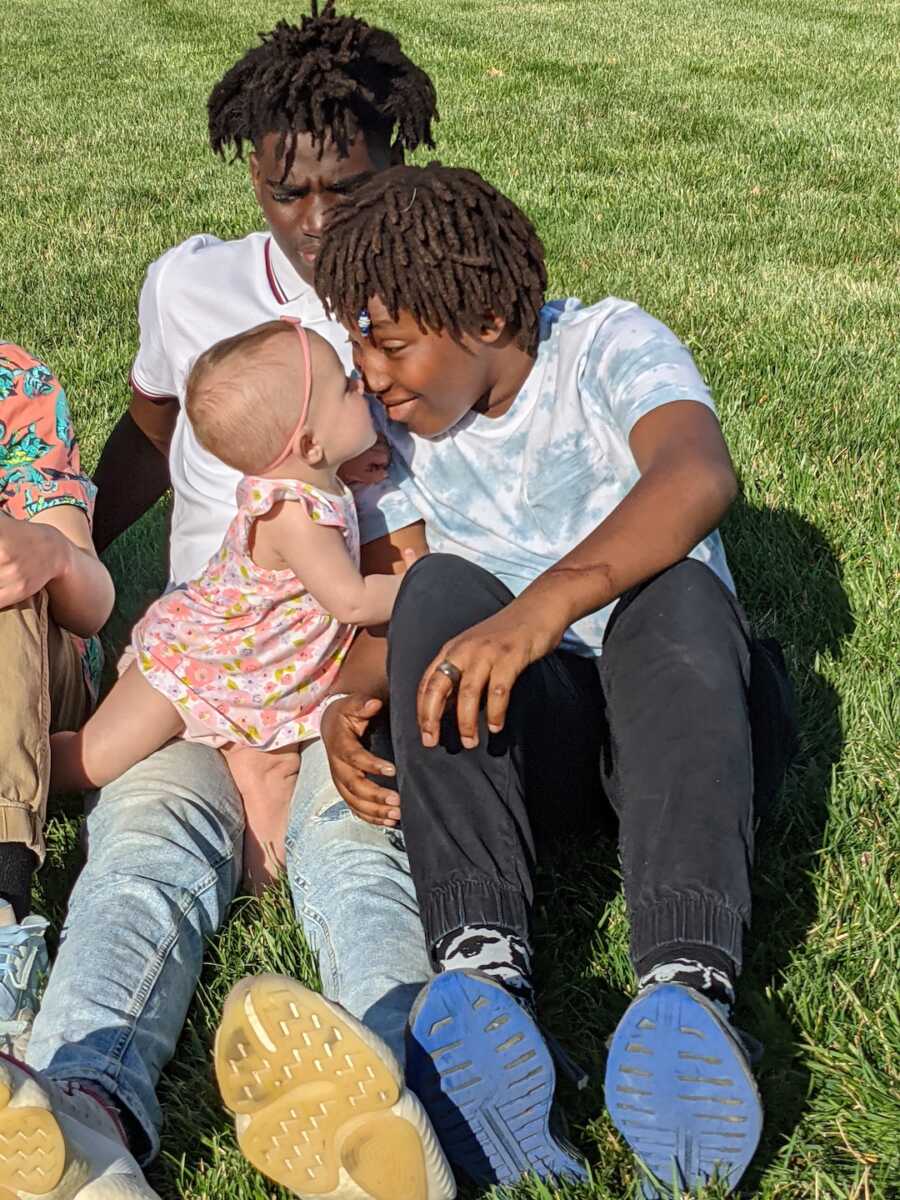 adoptive sons sitting in grass with their adoptive sister