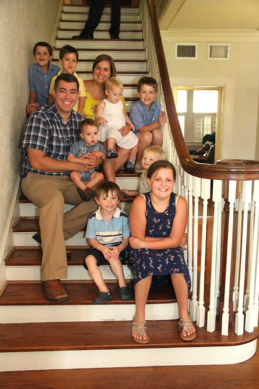 family gathers on stairs together on adoption day of their children