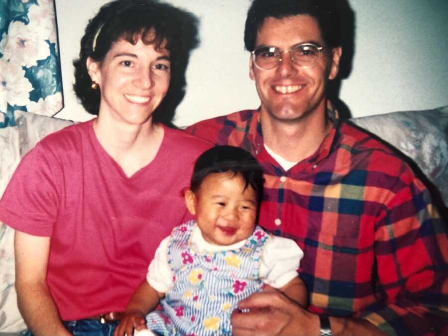 adoptive parents hold Korean adoptee infant on laps