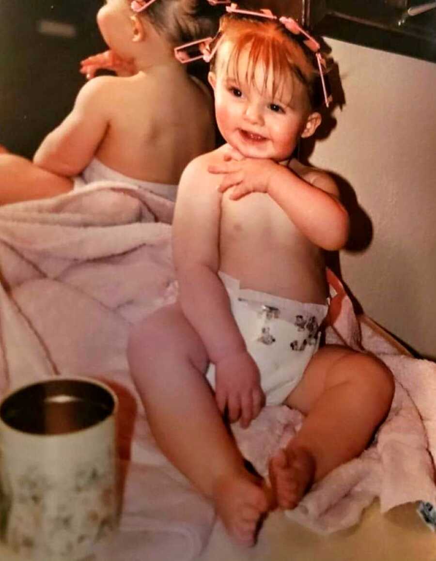 child abuse survivor as a baby sitting on pink blanket wearing a diaper