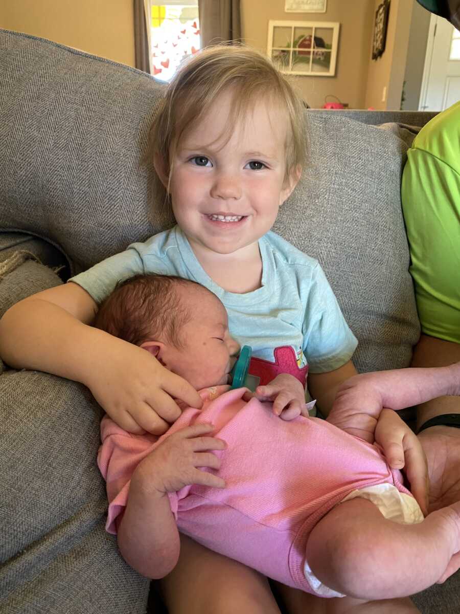 big sister holding her foster sister in her lap on couch