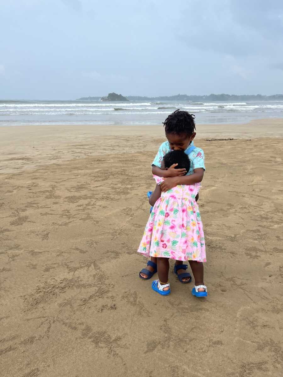 adoptive siblings hug each other while on the beach