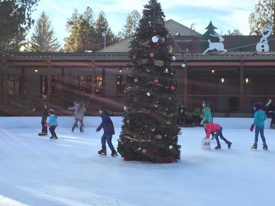 children ice skating around a Christmas tree