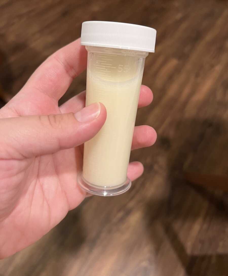 hand holding container of breast milk