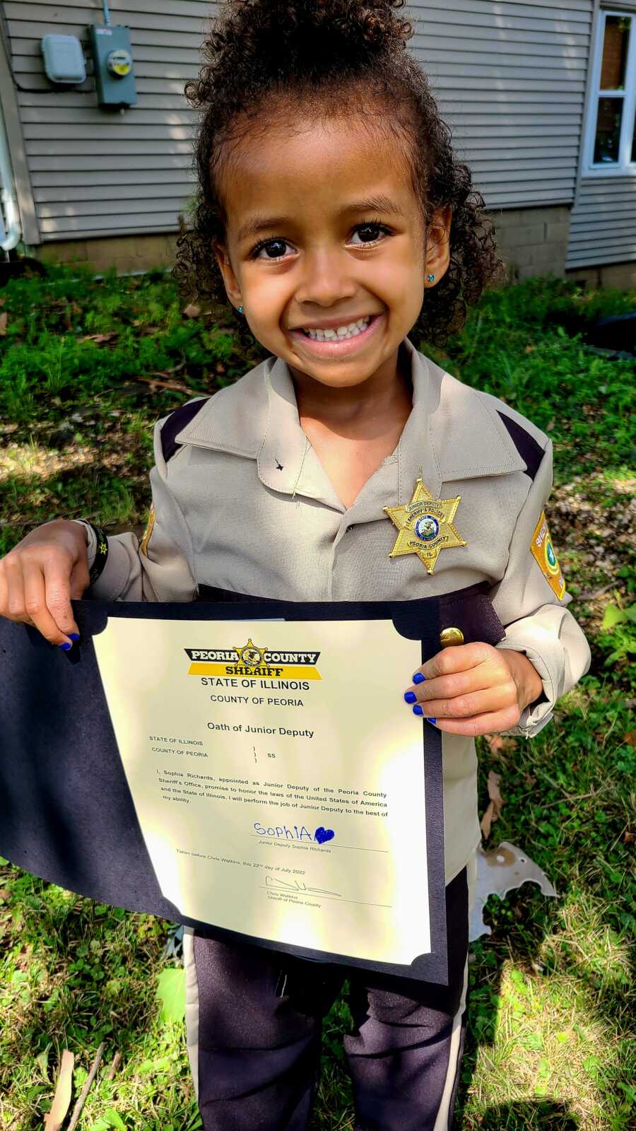 Young daughter holding junior sheriff certificate wearing sheriff uniform costume