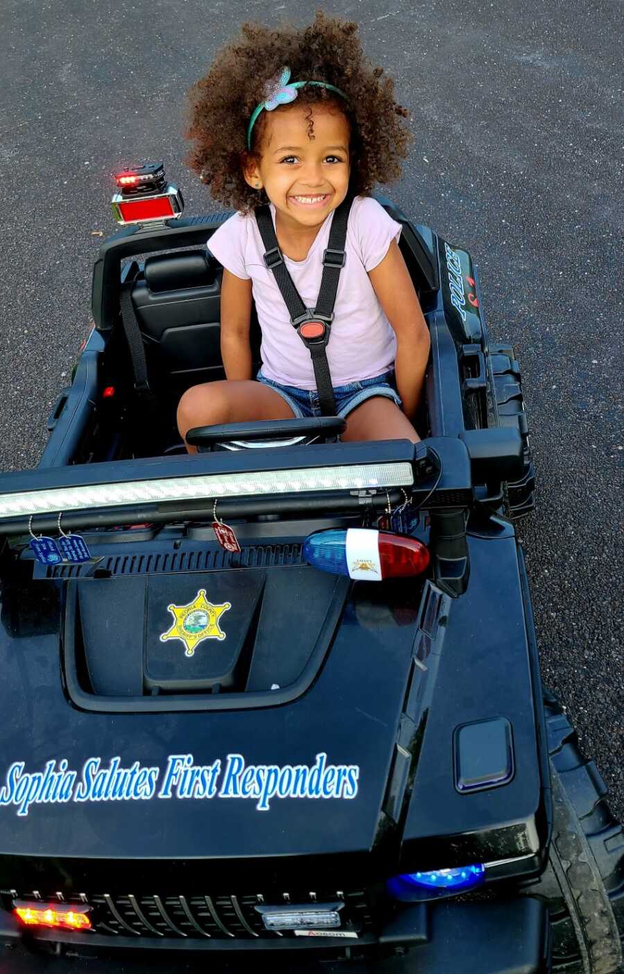 toddler daughter buckled in mini black sheriff car