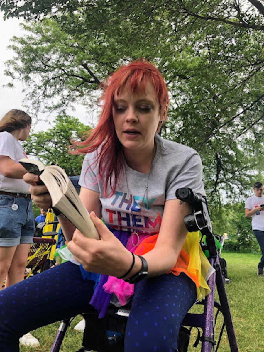 person with chronic illness sitting on walker while in park reading