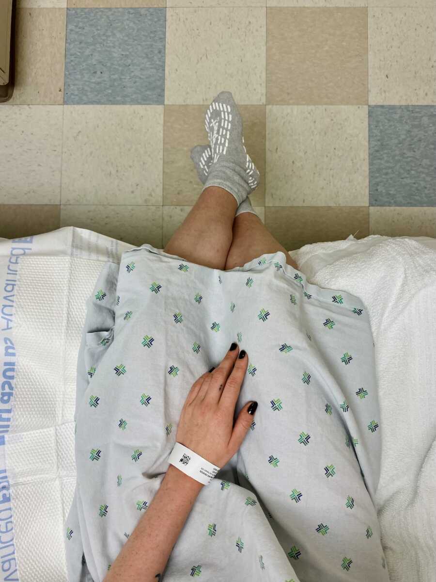 legs of woman with endometriosis sitting on hospital bed in gown